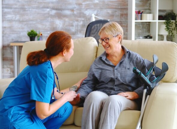 Female nurse talking with old woman with alzheimer in nursing home